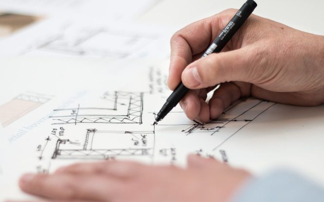 Ruka architekta kreslící půdorys domu nad výkresovou dokumentací